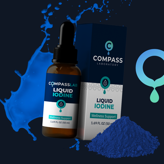 A bottle of Compass Lab Liquid Iodine next to its retail box, with a pile of blue powder and a blue liquid splash graphic on a dark background.